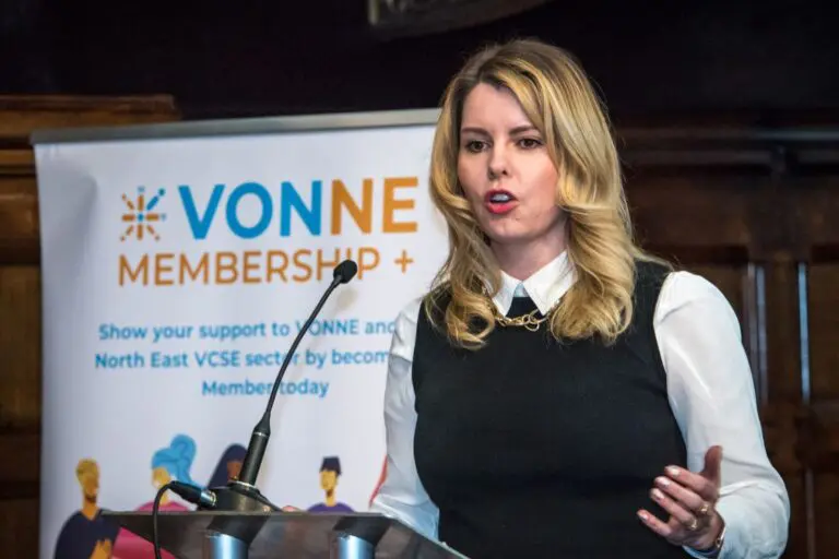 Kim McGuinness speaking at podium with VONNE logo in background.