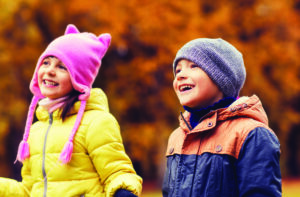Two children in winter clothes with autumnal background