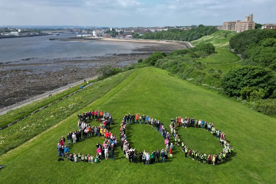 large group of people making up the number 800 on large grass area with river Tyne and North Shields in the background.