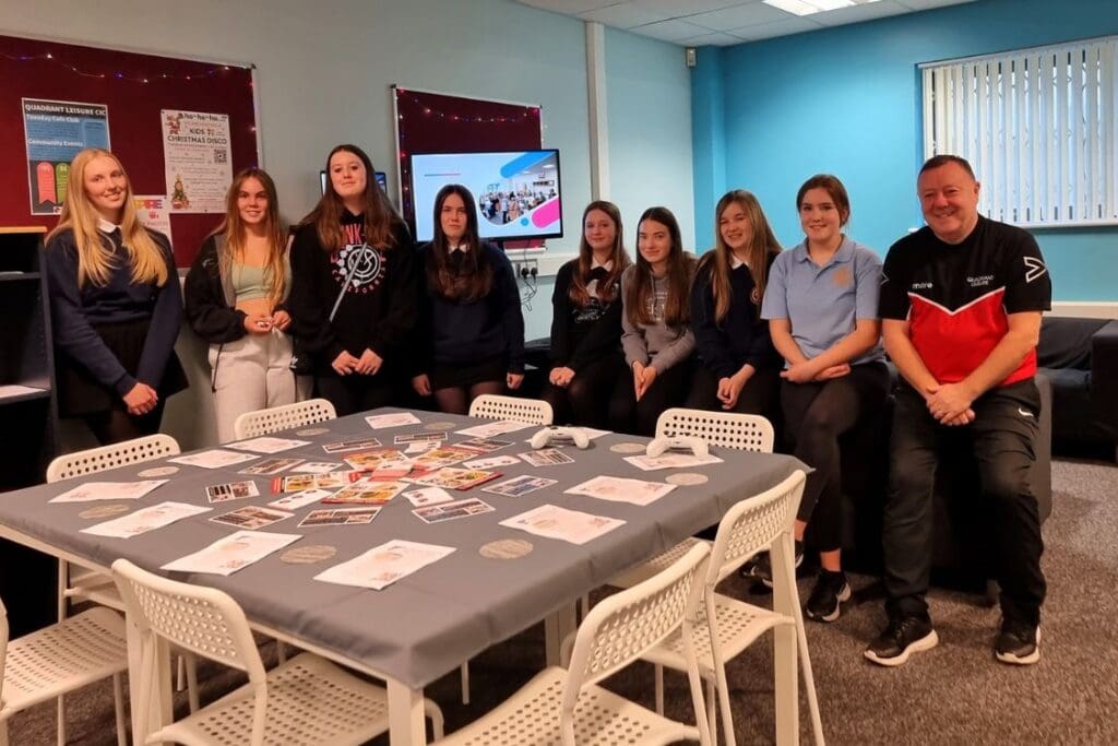 Group of young girls sat in their new youth room. There is a large table and chairs in the foreground.