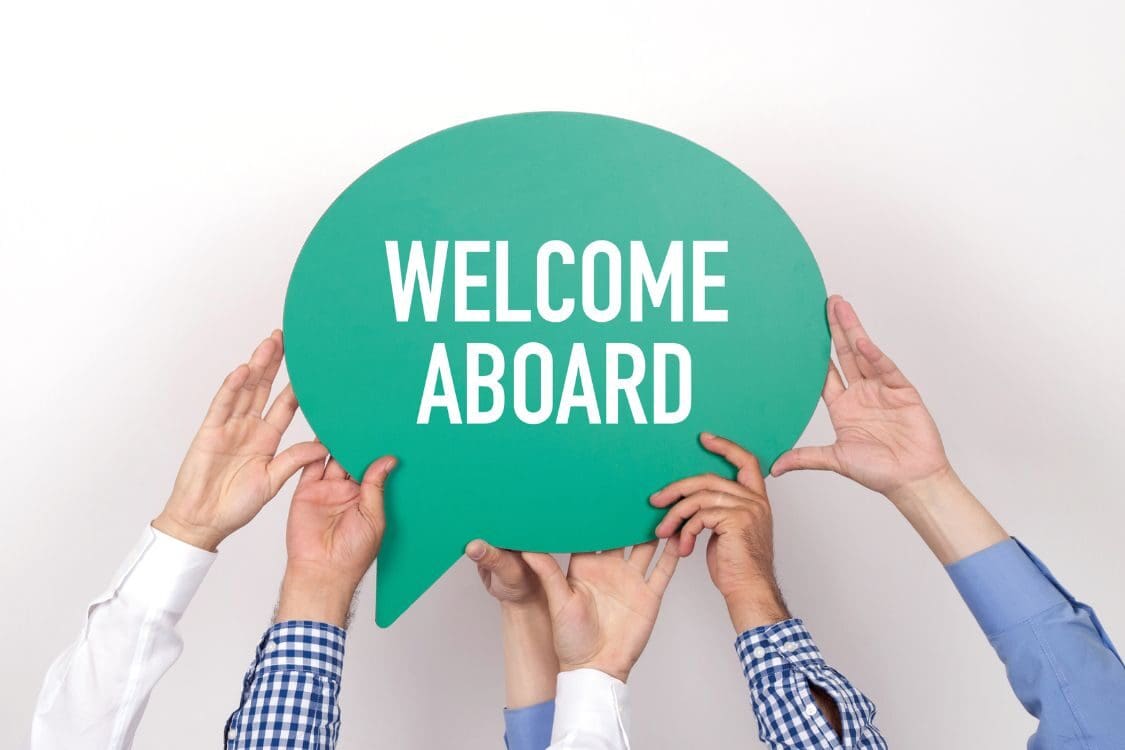 A group of diverse hands holding a sign that reads "WELCOME ABOARD."