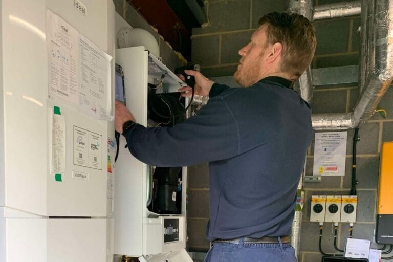 Man in blue jacket inspecting a boiler