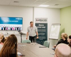 Man standing presenting to a group of people.