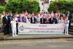 Large group of sports people behind a banner saying So Iran - Special Olympics World Games Berlin 2023