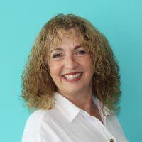 Profile pic of Tracy. She has blonde curly hair and a white shirt.